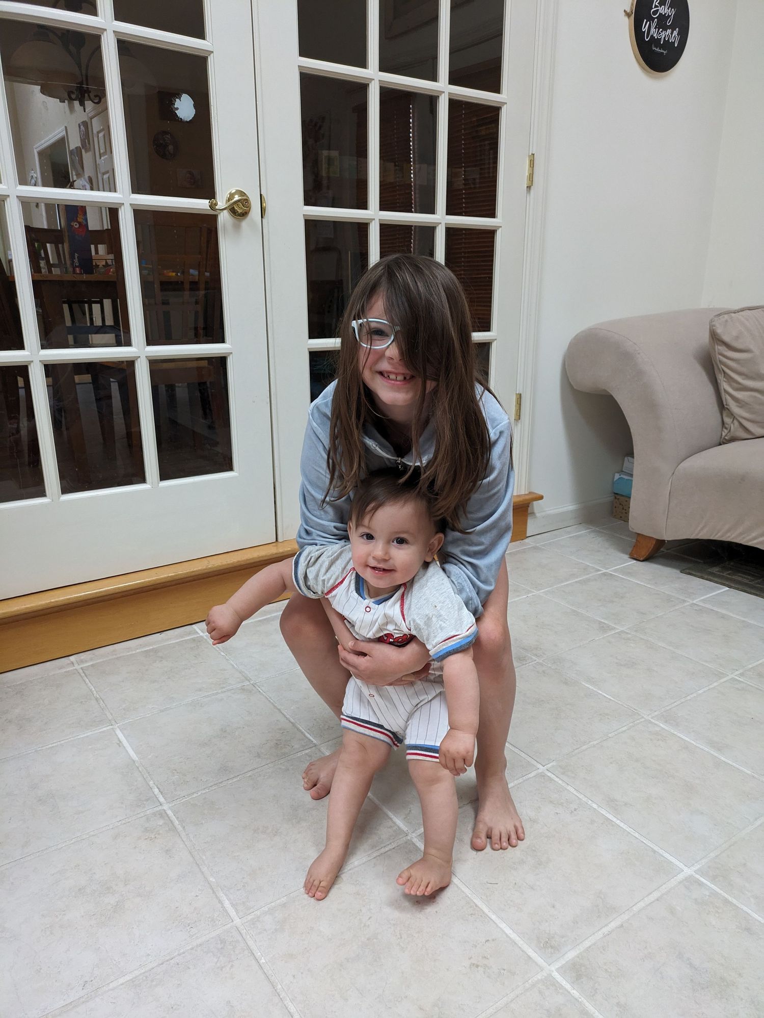 A sequence of photos shows a toddler and adult playing a hopscotch-like game with tape markings on a light floor.