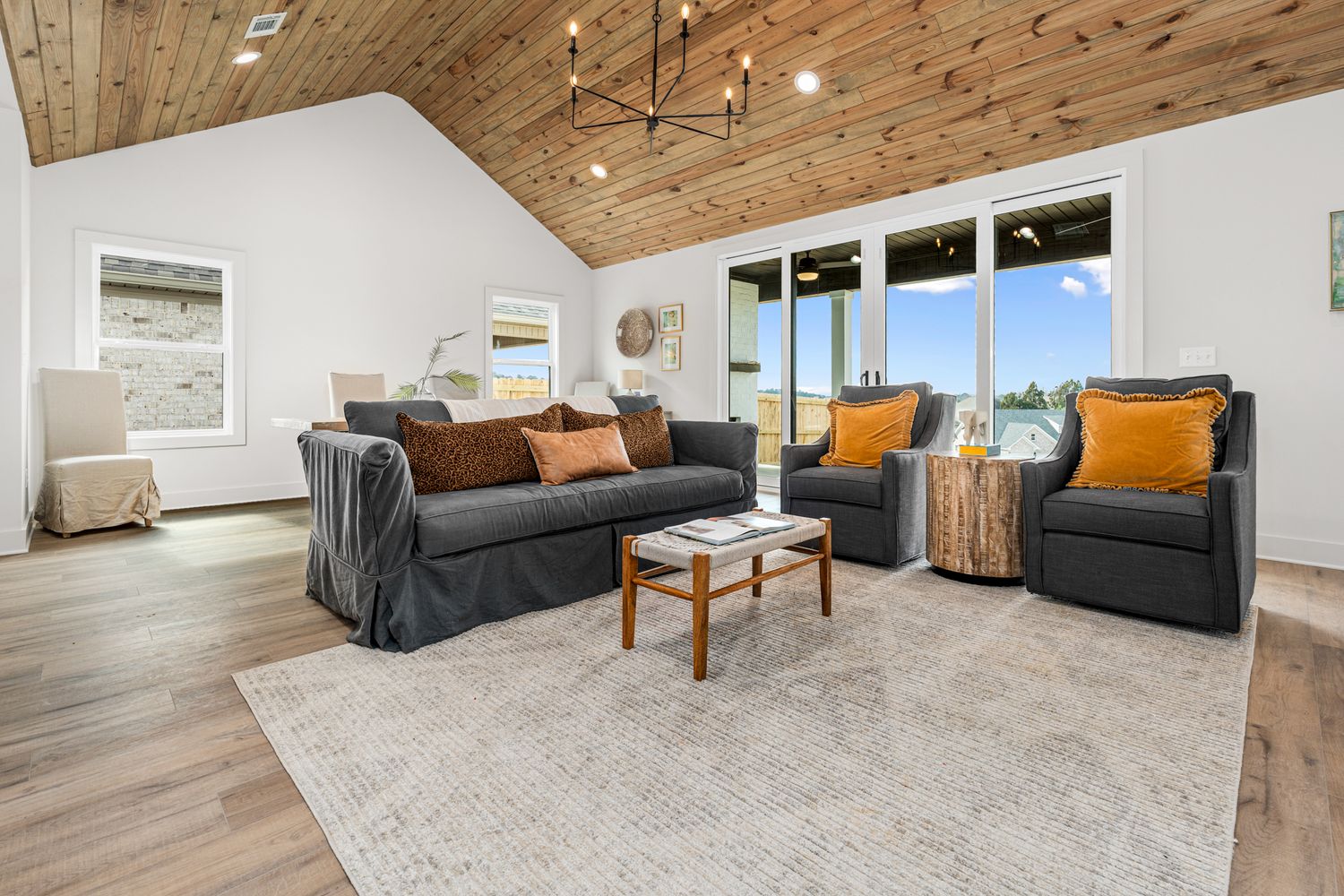 Spacious living room with vaulted wood ceiling, string lights, and modern furniture.