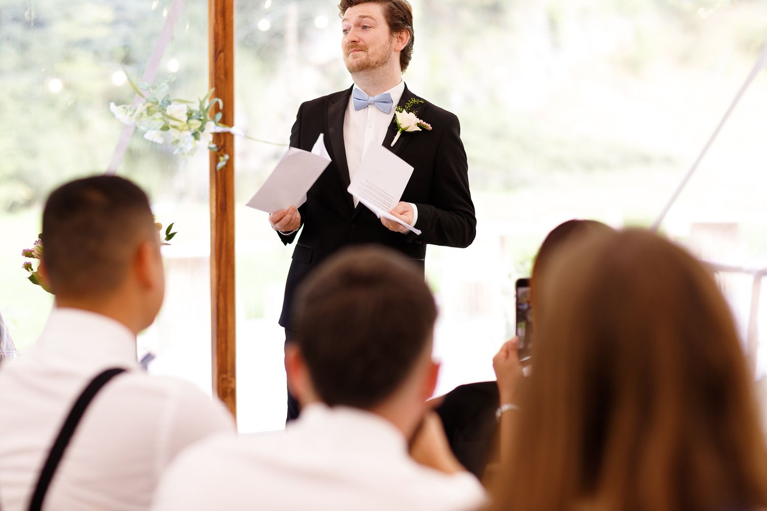 Wedding guests watch attentively as a couple performs their first dance at an outdoor tented reception.