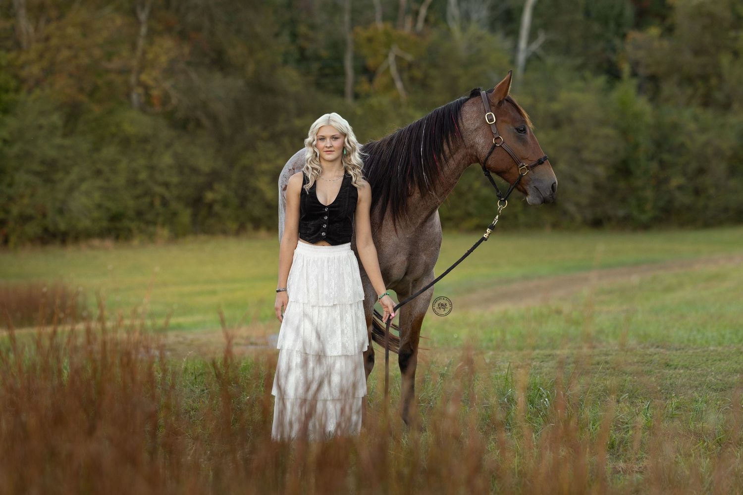 Girl laying in a field of tulips posing with her horse