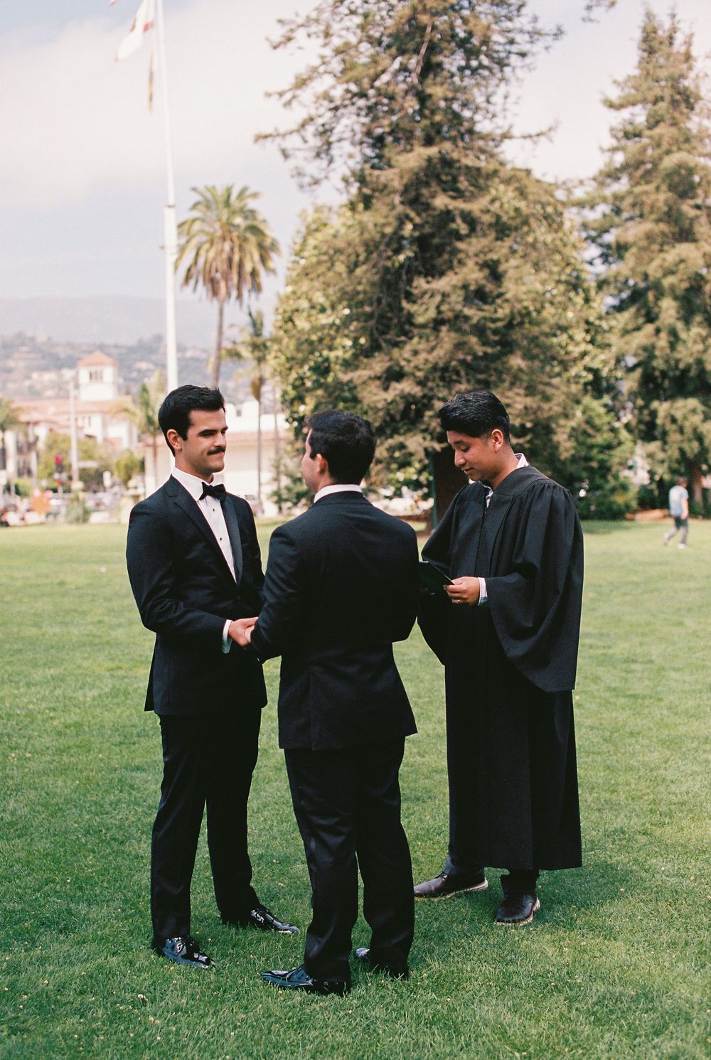 A 35mm film photo of two grooms exchanging vows on the lawn of the Santa Barbara Courthouse.