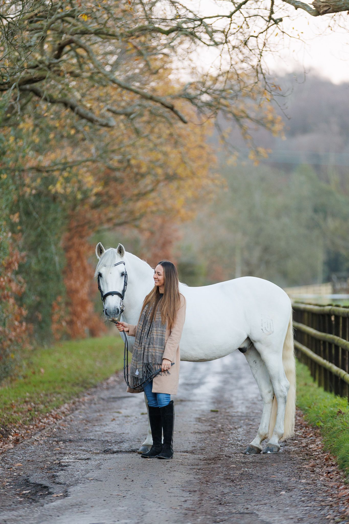 A horse and its rider enjoy an outdoor photoshoot session near rustic wooden fencing on a sunny day.