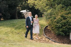 Couple walking together on landscaped garden path during outdoor celebration.