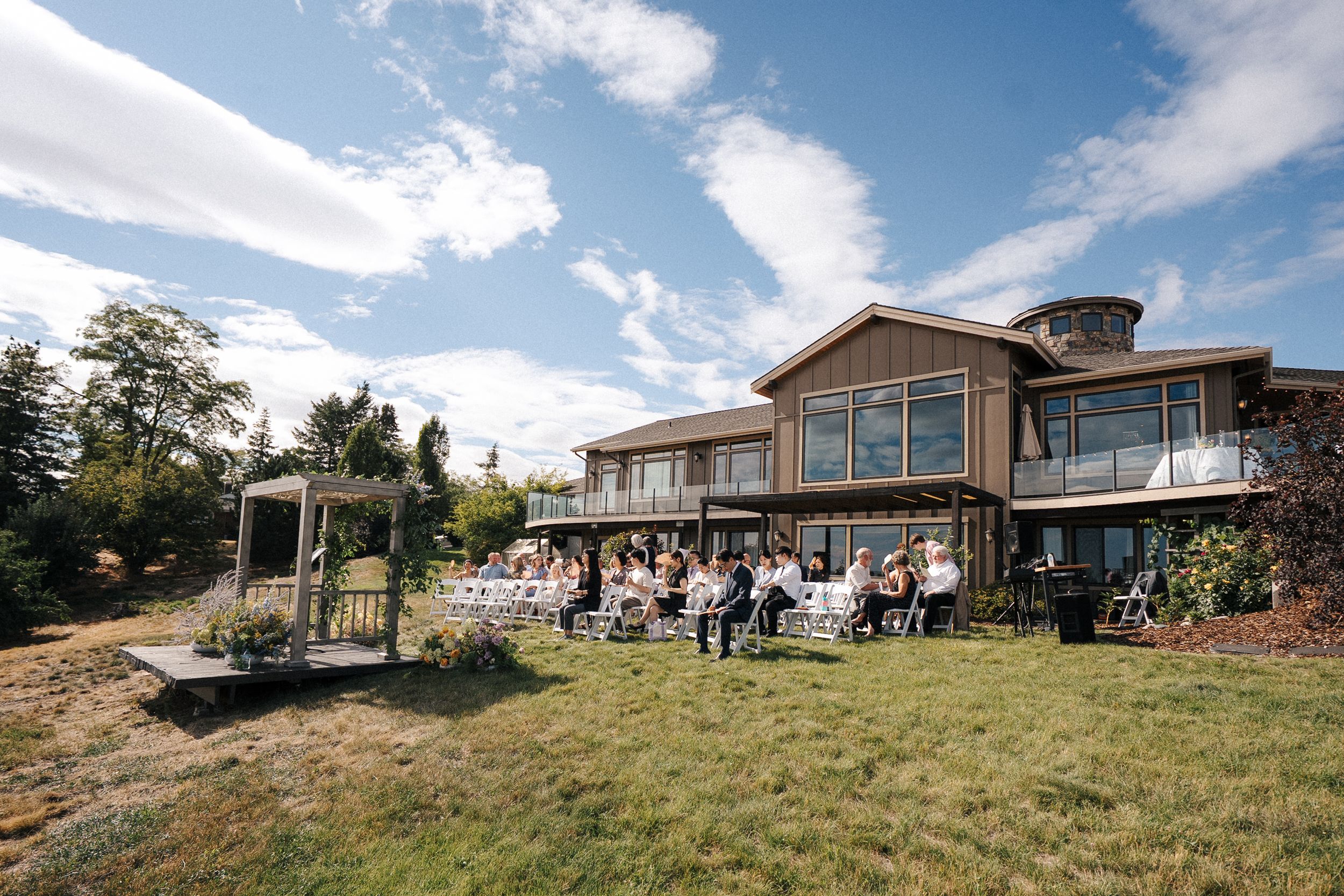 Modern hillside venue with panoramic mountain views under bright blue skies and white clouds.