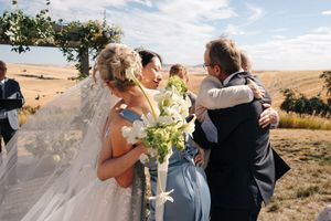 Wedding celebration in scenic countryside with rolling hills and blue sky backdrop.