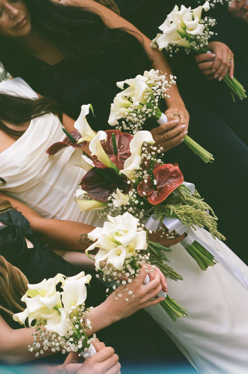 Close-up sequence showing hands arranging white calla lilies and baby's breath in an elegant wedding bouquet.