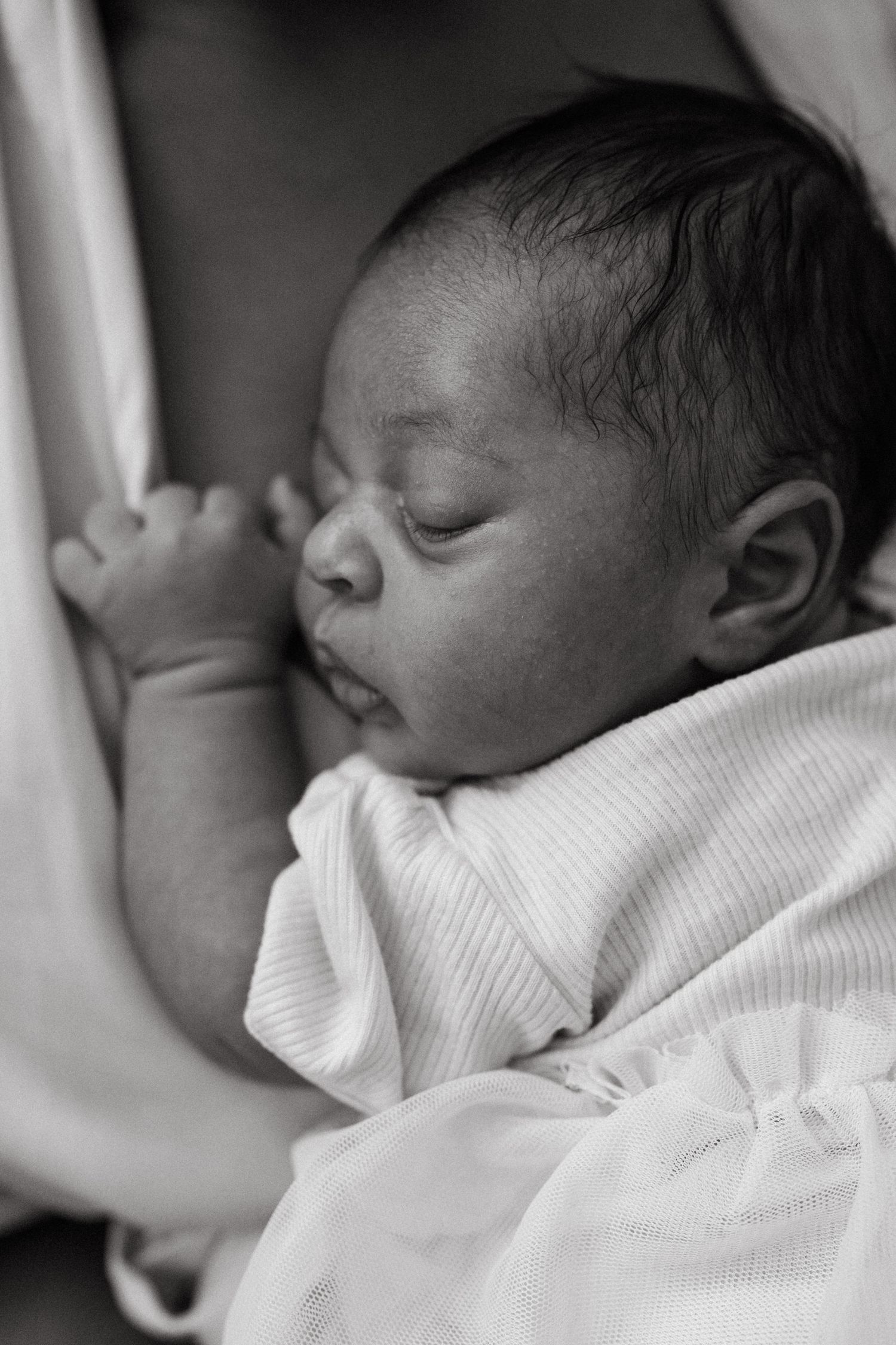 Black and white close-up photos of a sleeping newborn baby wrapped in white fabric.