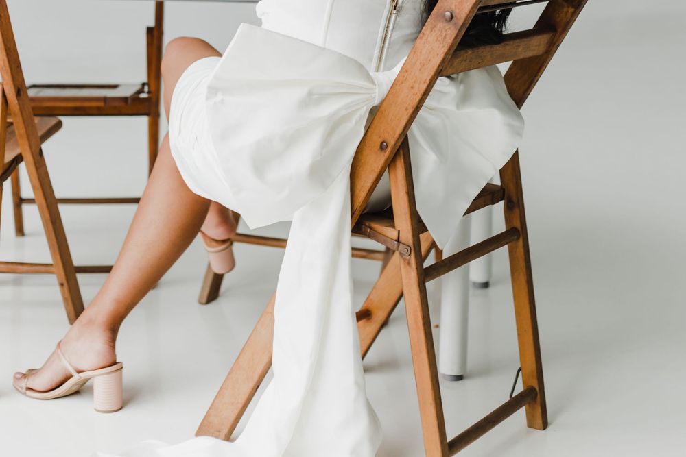 Detail shots of wooden chairs and white dress during minimalist studio photography session.