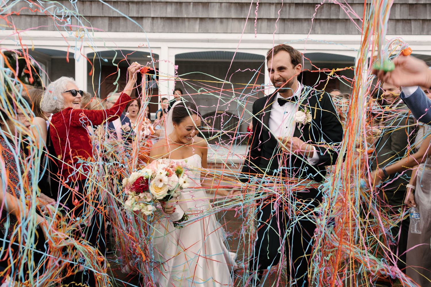 A joyful wedding celebration with colorful streamers and confetti flying through the air as a couple exits their ceremony.