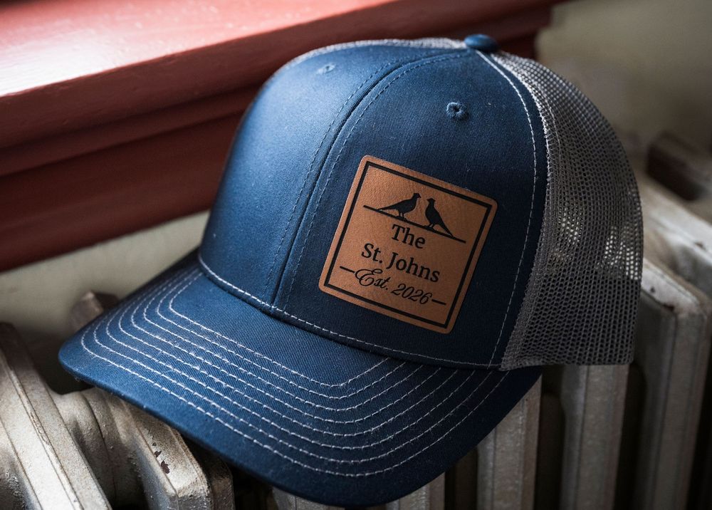 Row of blue trucker hats with leather patches displayed on a white surface.
