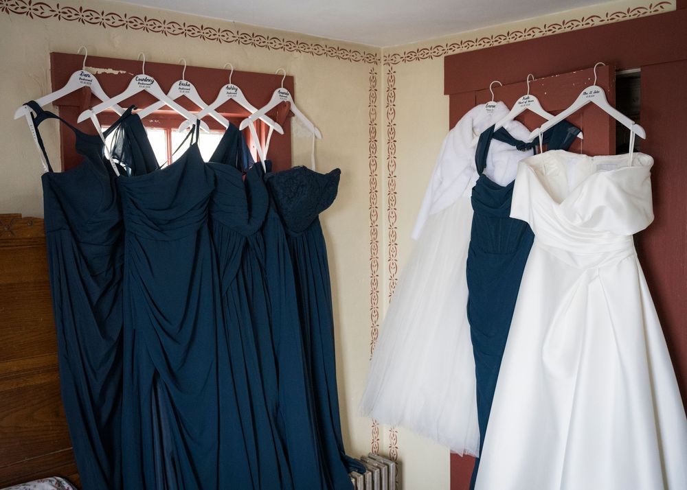 Row of navy blue bridesmaid dresses and white wedding gown hanging on display.