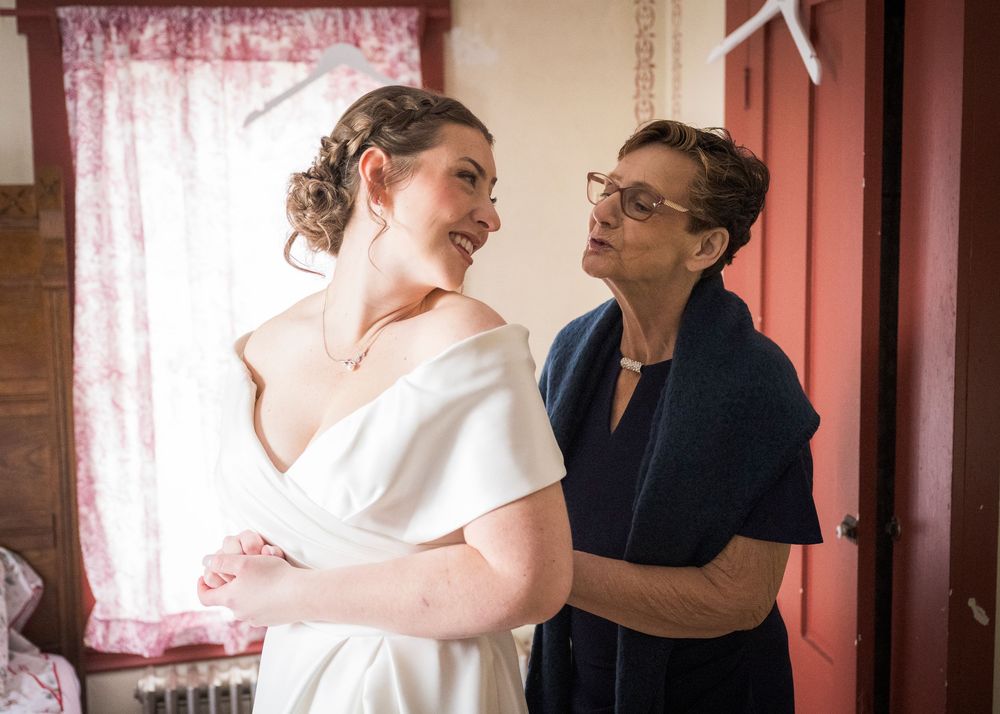 Intimate getting ready moment in room with pink curtains and natural light.
