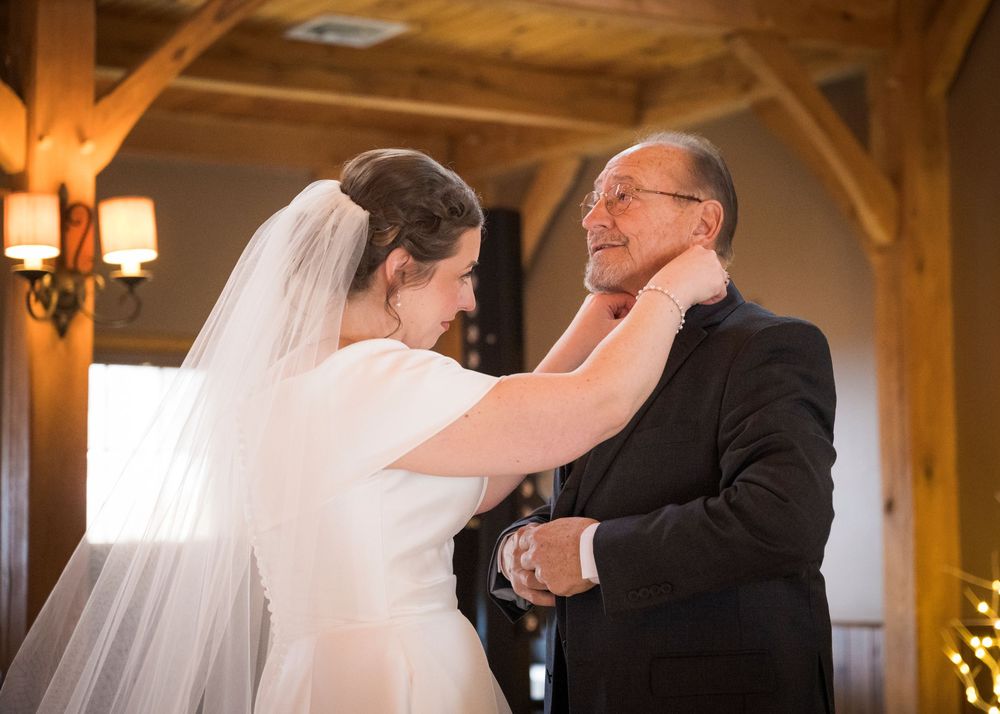 Wedding couple shares an intimate dance moment in a rustic barn venue with wooden beams.