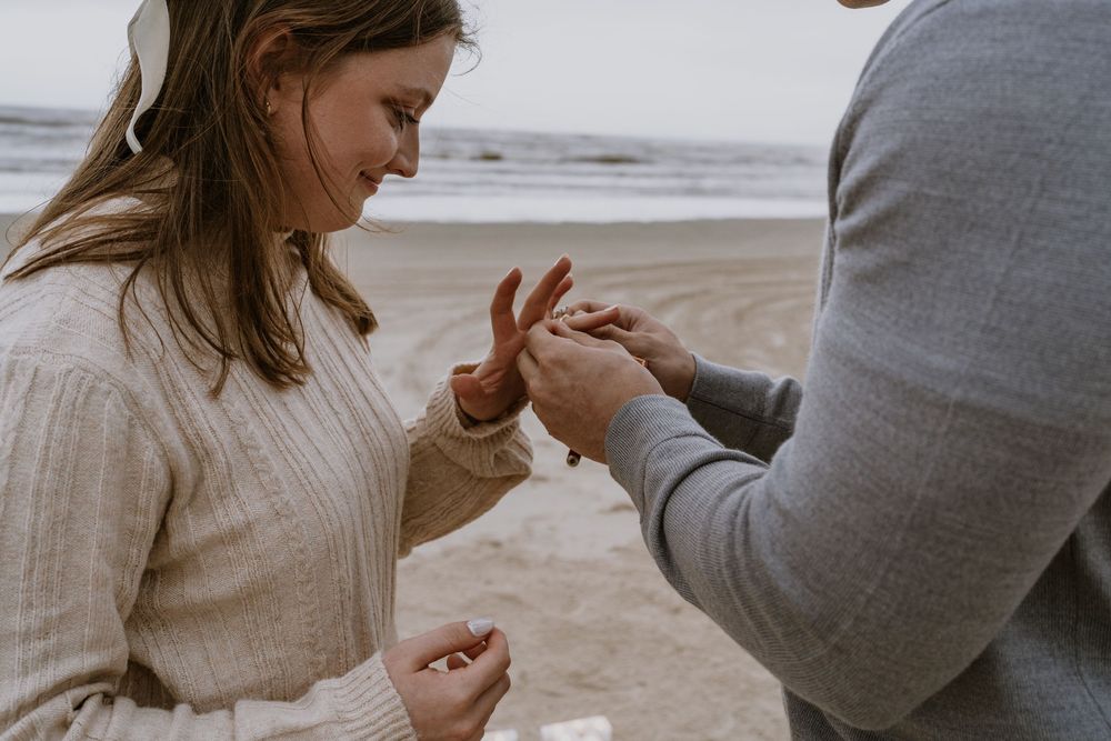 Close-up of hands during a beach proposal moment.
