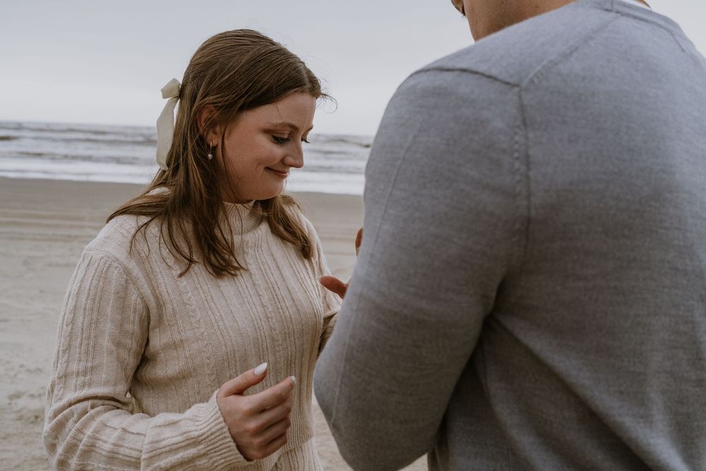 An emotional moment during a beach proposal with two people looking at a ring.
