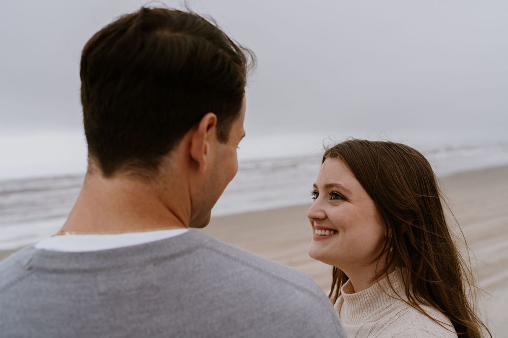 A couple shares a romantic moment together on a cloudy beach.