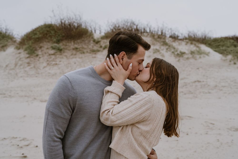 A couple shares an intimate embrace on a misty beach.