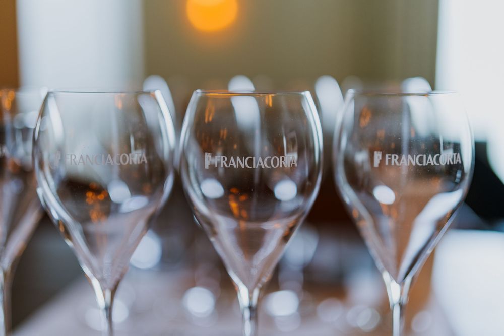 Row of empty wine glasses lined up on white tablecloth.