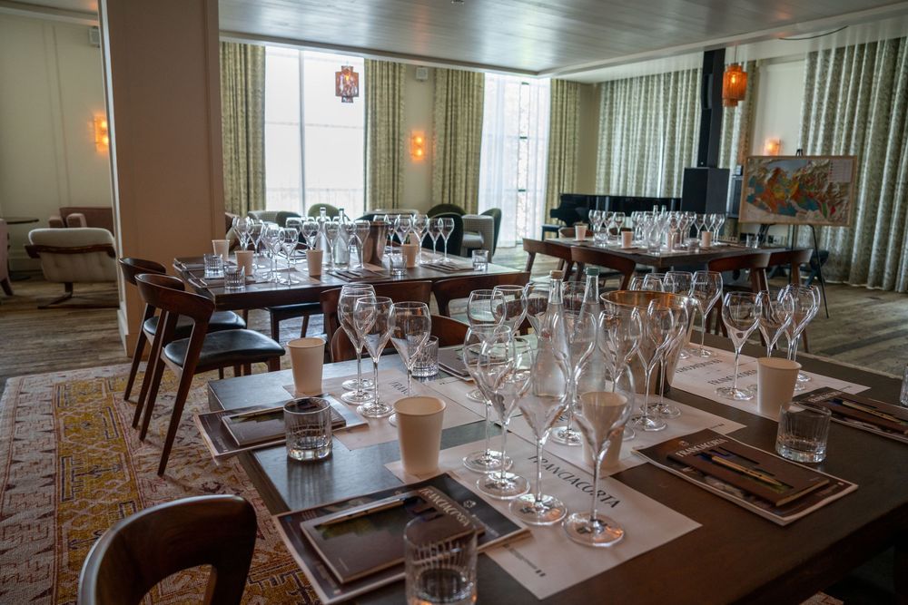 Elegant dining room setup with wine glasses and place settings on round tables.