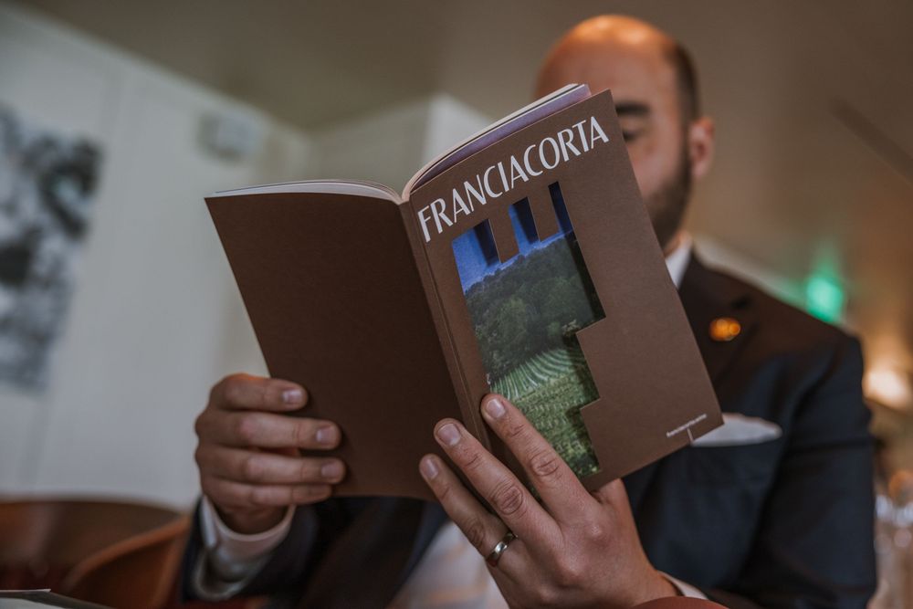 Someone reading a Franciacorta wine menu or guidebook.