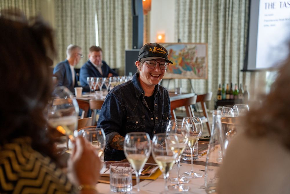 Wine tasting session with attendees sampling beverages at formal dining setup.