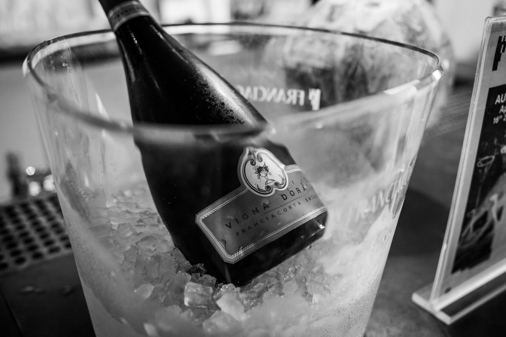 Black and white image of wine bottle chilling in crystal ice bucket.