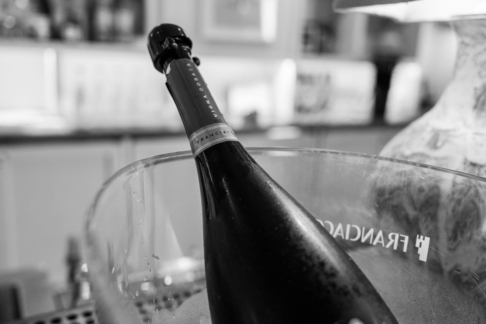 Close-up black and white shot of wine bottle neck against blurred background.