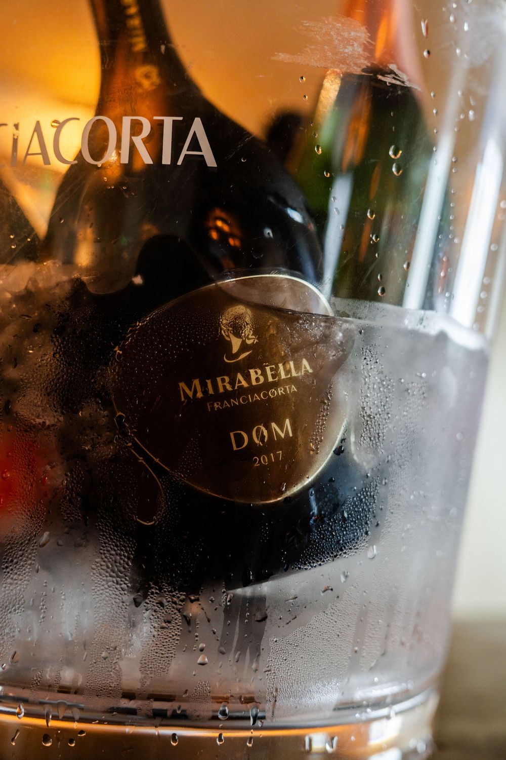 Close-up of wine bottles in an ice bucket showing condensation on glass surfaces.