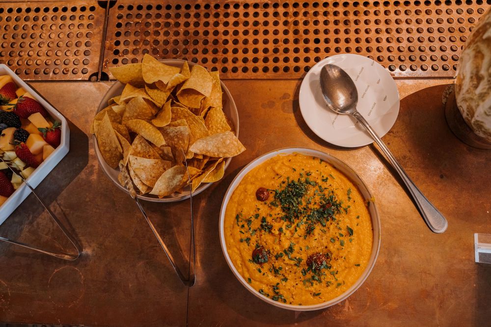 Overhead view of tortilla chips and vibrant orange queso dip served in bowls.