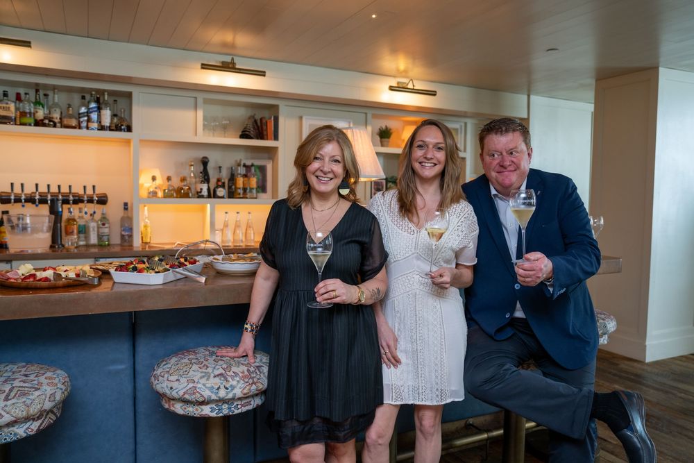 Group enjoying drinks at an elegant bar with bottles displayed in background.
