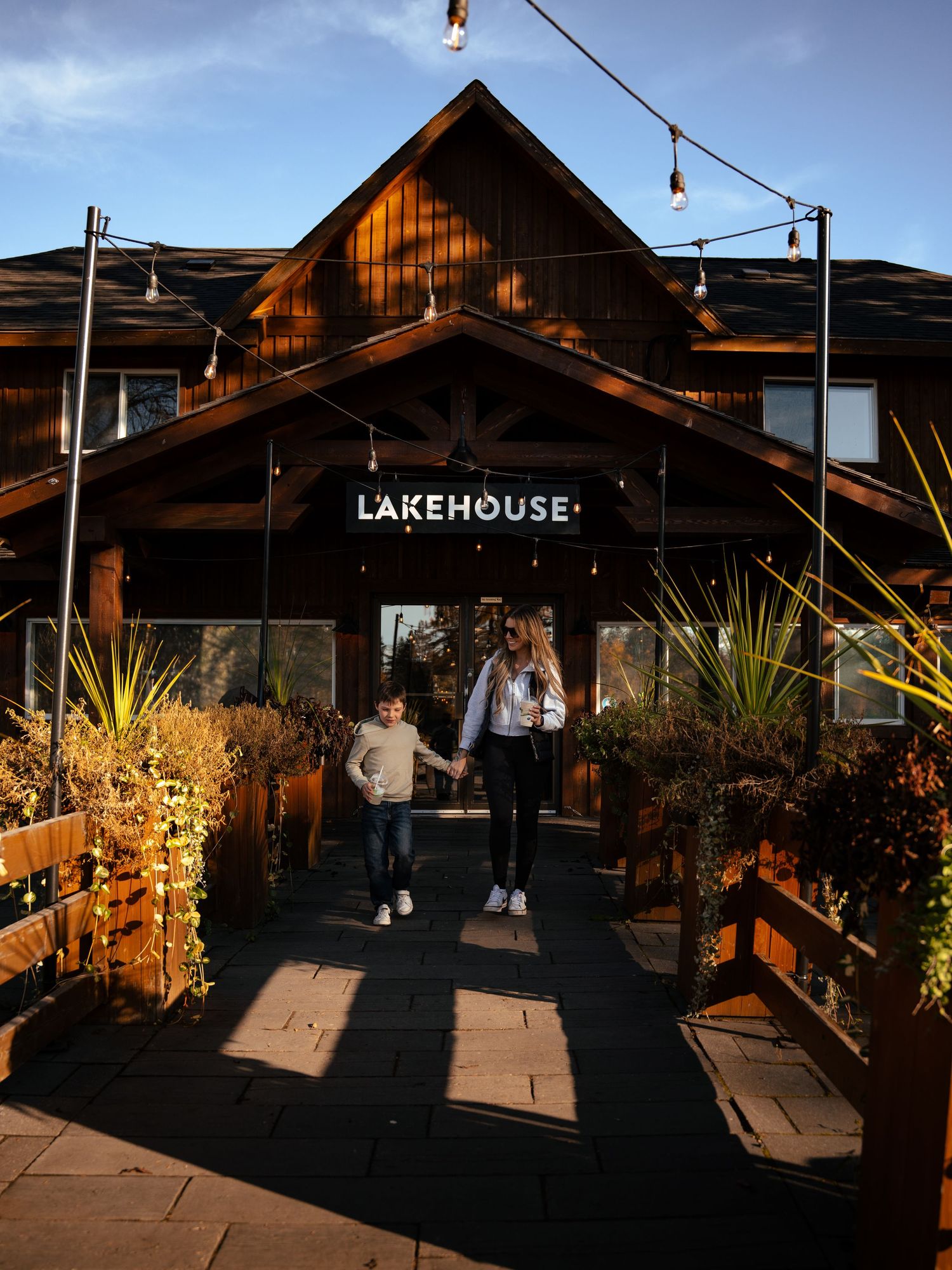 Rustic lakehouse exterior with string lights and wooden deck at dusk.