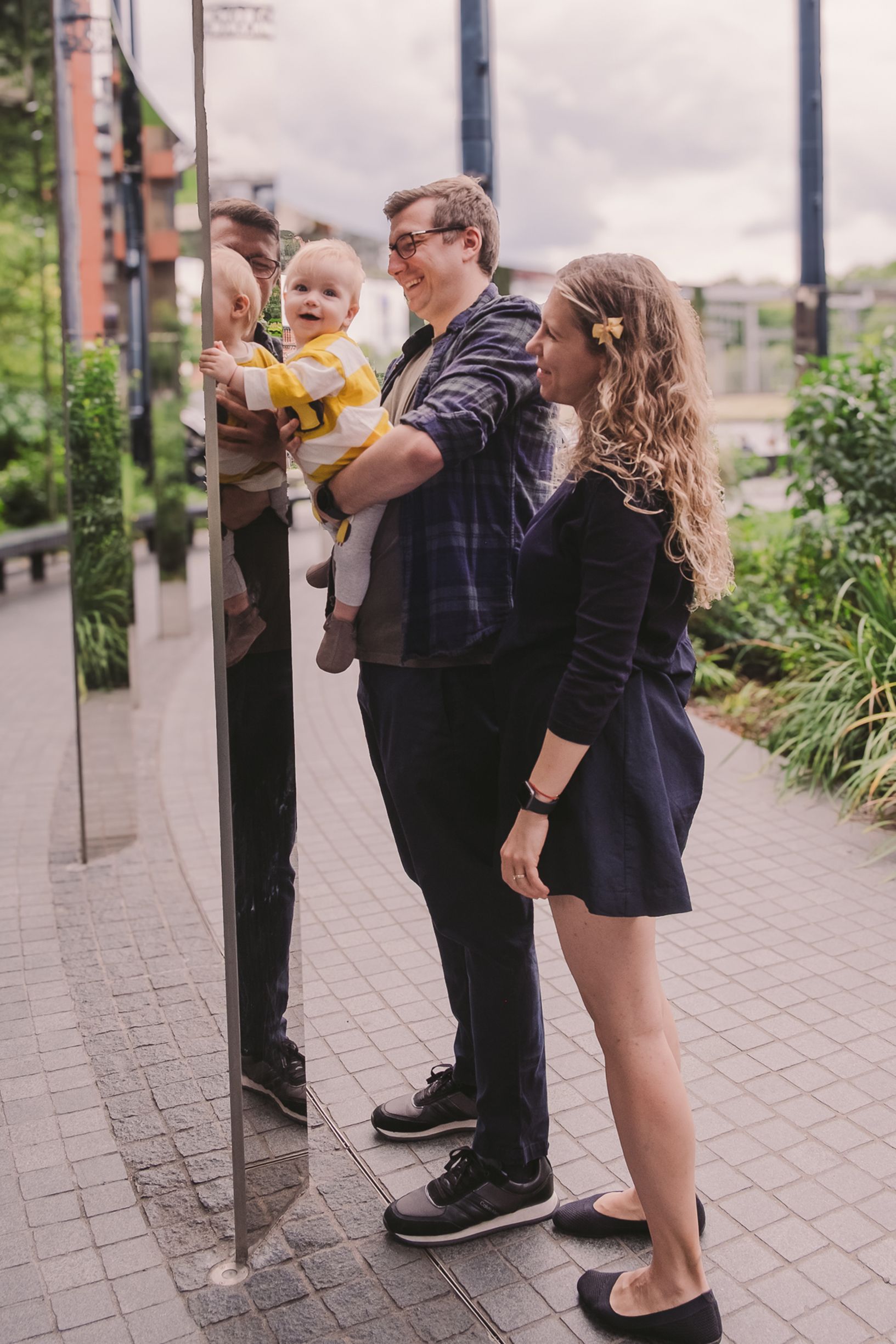 A candid moment captured on a sidewalk with urban landscaping and buildings in the background.