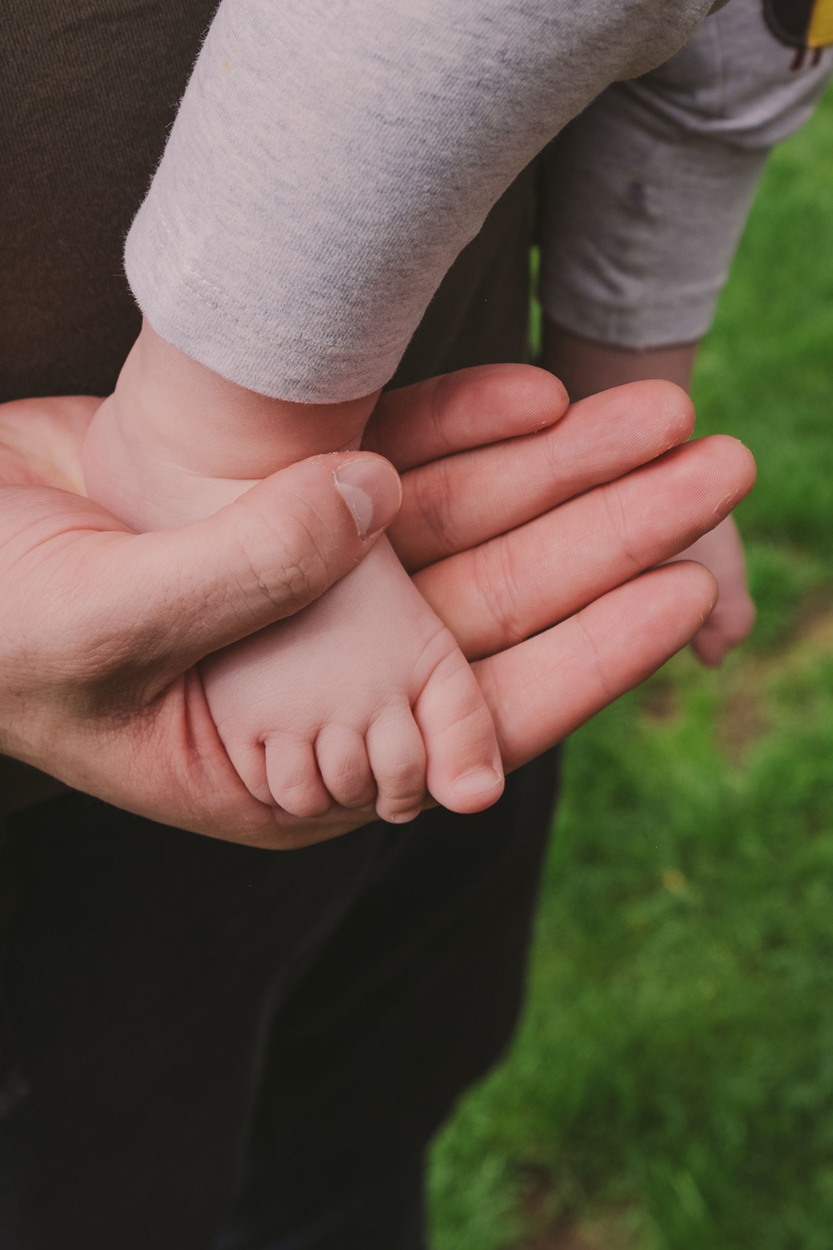 Close-up view of tiny baby feet being gently held by adult hands.
