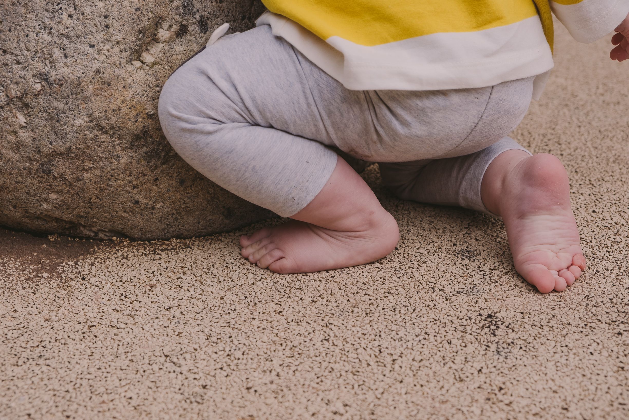 Detail shot of tiny feet on rough concrete surface.