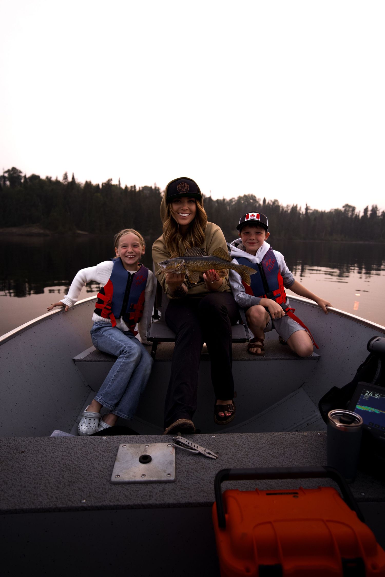 Group relaxing on a boat dock during sunset over a peaceful lake.
