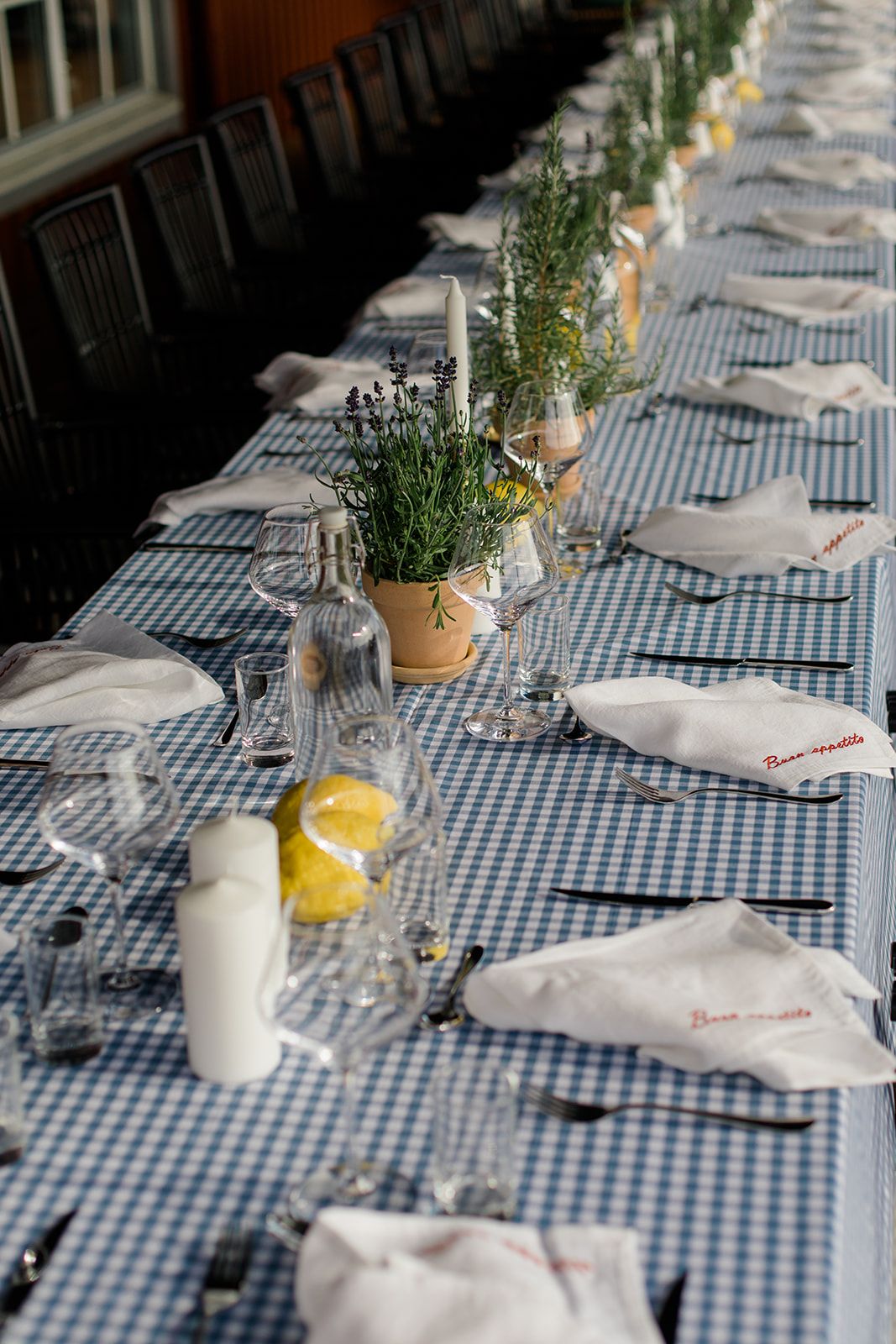 Table settings with blue gingham tablecloth, white napkins, and yellow citrus centerpieces create a fresh dining atmosphere.