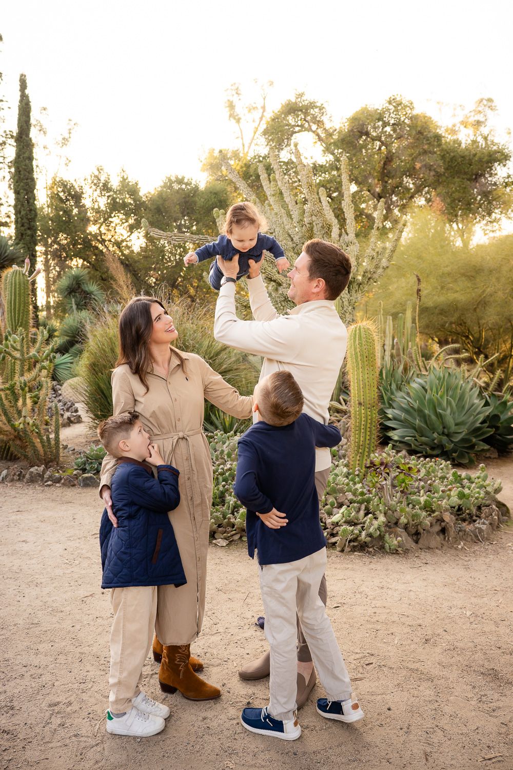 Family holds baby in the air during their family photo session as their older children look on