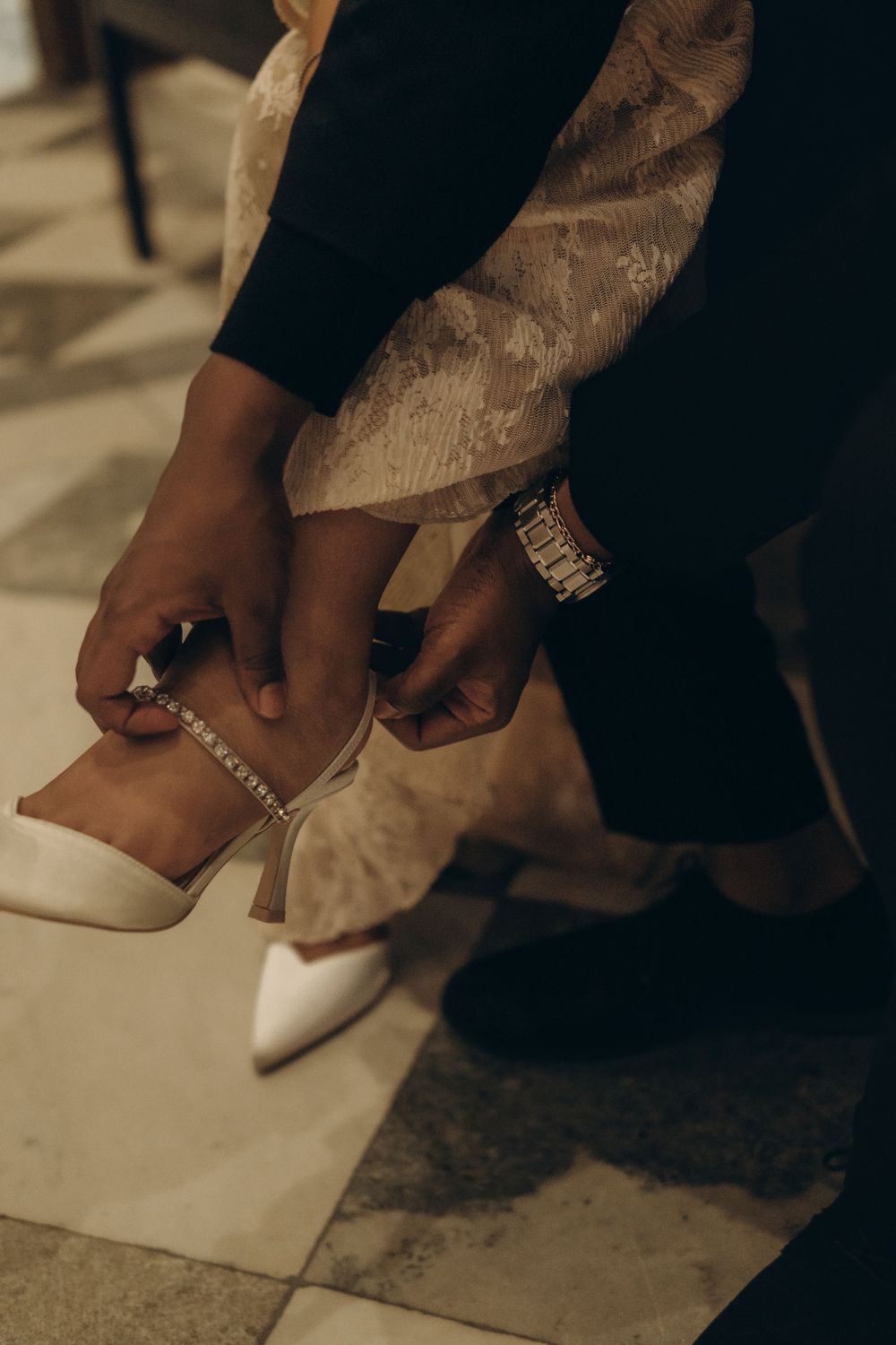 detail of groom helping his bride put on wedding shoes while being captured by storytelling wedding photographer in Stockholm