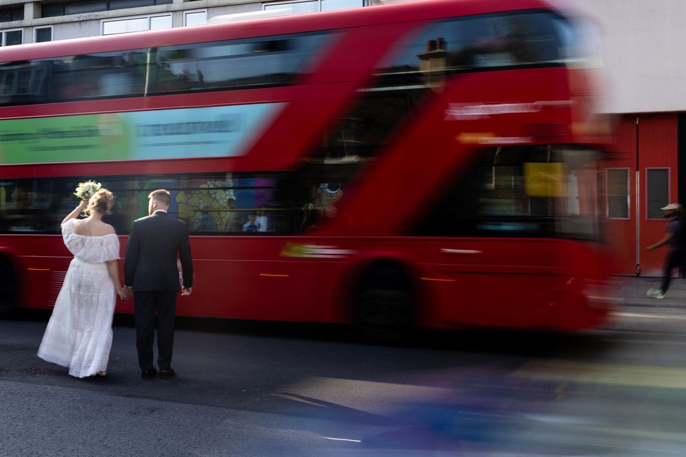 Red double decker buses create motion blur streaks against an urban backdrop.