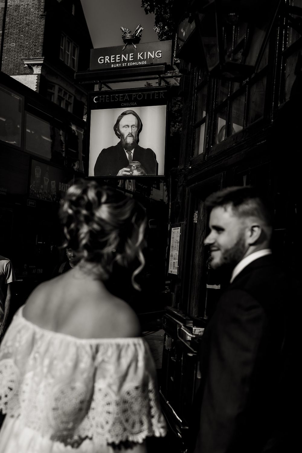 A couple in wedding attire stands together in a dimly lit pub or restaurant setting.