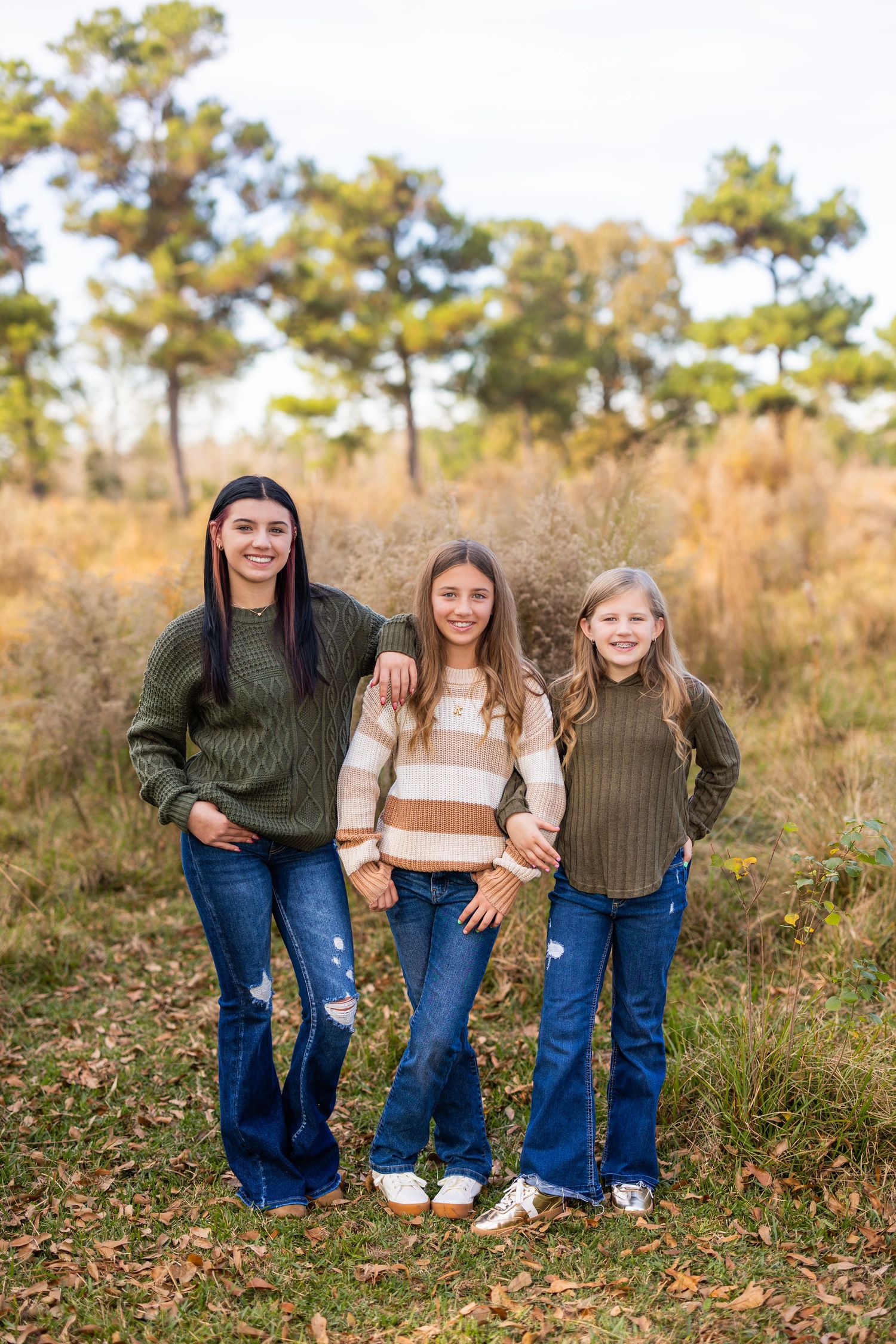 Group of siblings in coordinating outfits pose in fall foliage.
