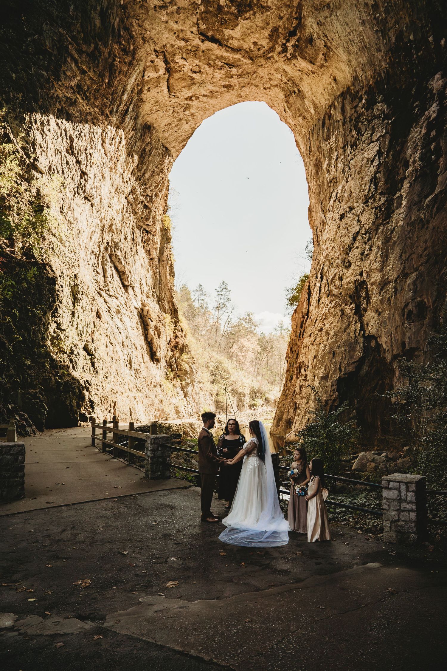 A wedding ceremony setup inside a dramatic natural cave opening with benches and natural light.