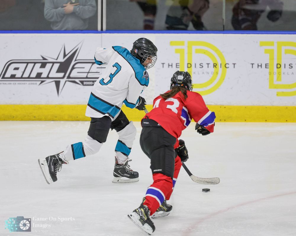 Hockey players compete for the puck during an intense game on the ice rink.