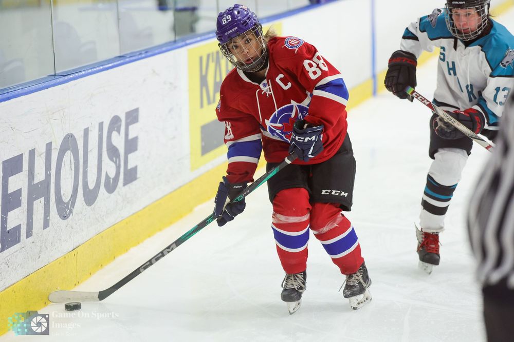 Hockey players battle for the puck along the boards during an intense game on the ice.