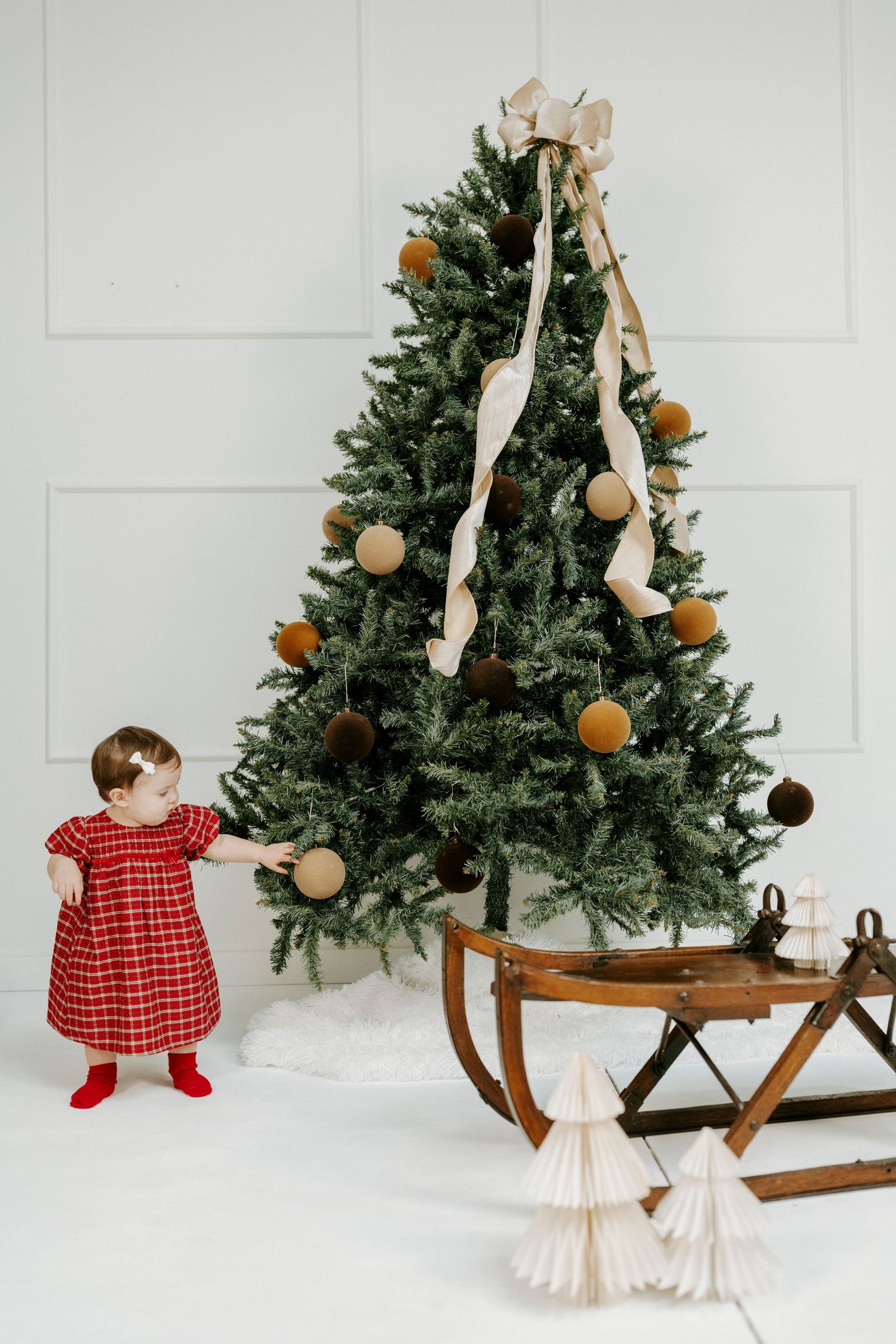 Christmas decorative scene featuring vintage wooden sled, evergreen trees, and ornate angel decorations.