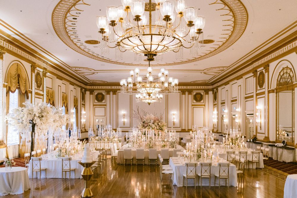 Elegant ballroom panorama with ornate chandeliers and classical architecture featuring white and gold decor details.