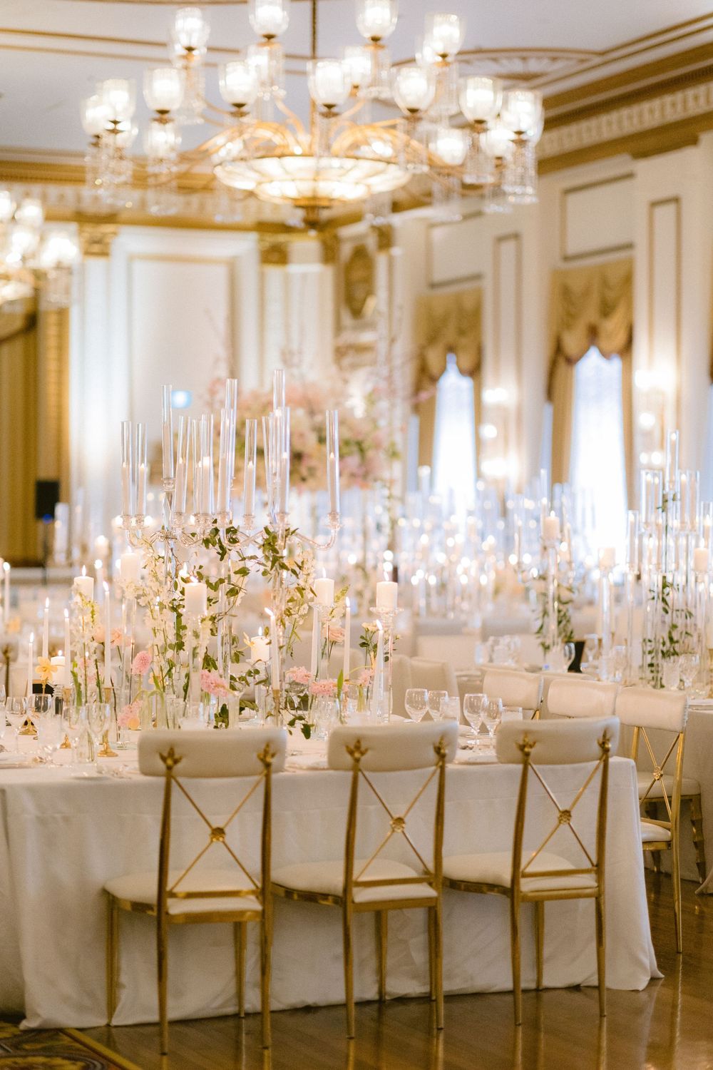 Long banquet tables adorned with tall candelabras and white linens in a classic ballroom setting.