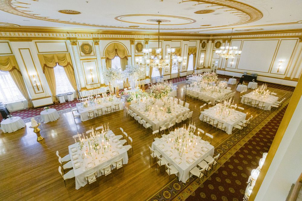 Panoramic view of an opulent ballroom with ornate gold ceiling details and multiple crystal chandeliers.
