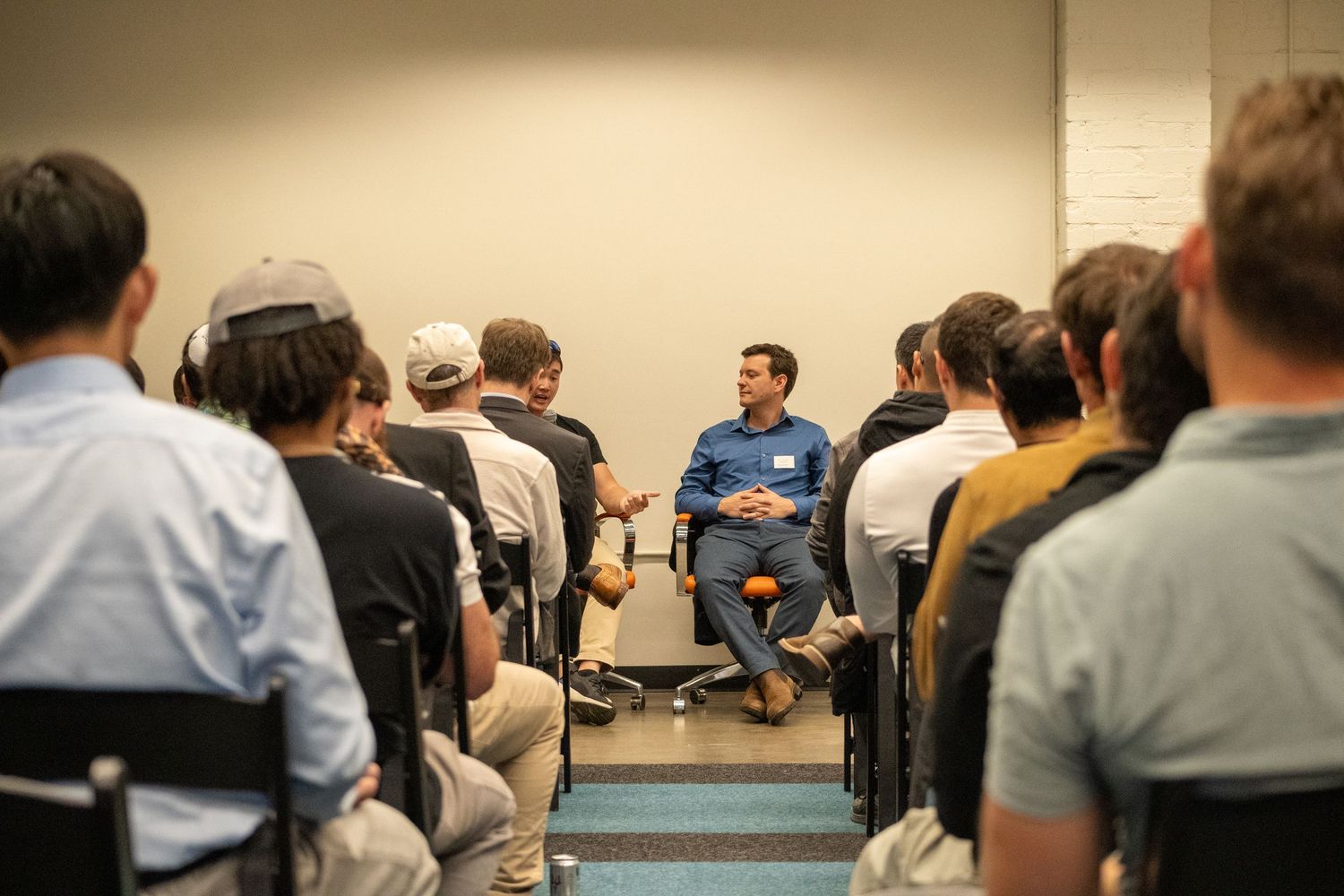People seated in rows during an indoor presentation or meeting.