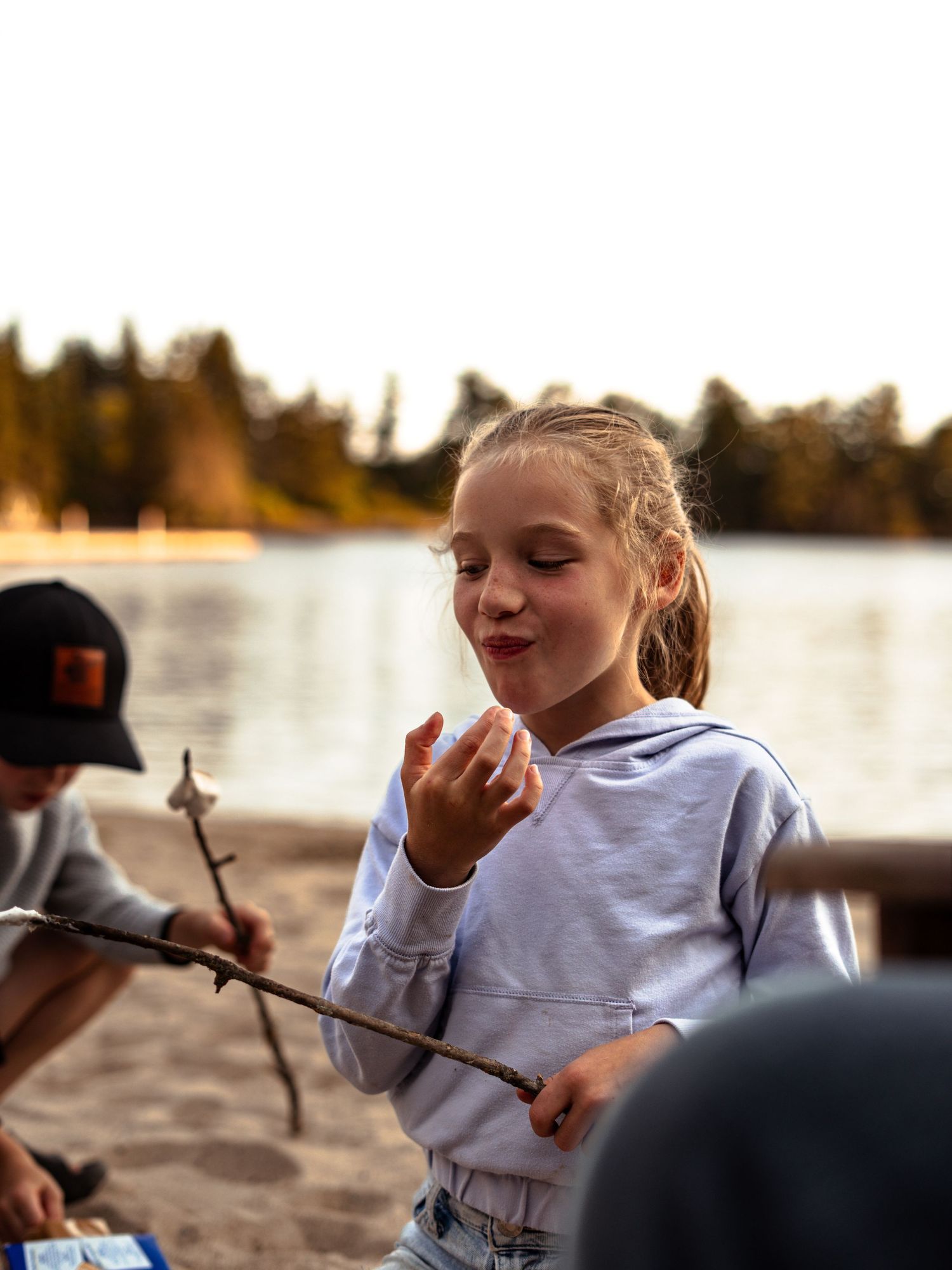Child enjoying snacks during outdoor lakeside activities at sunset.